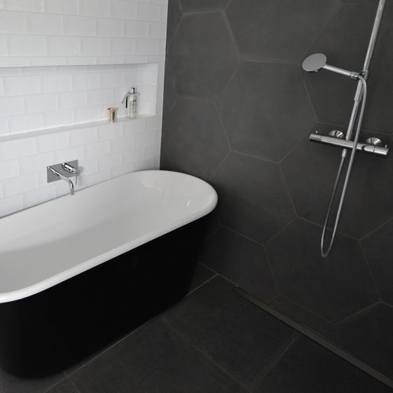 Hvitt og sort badekar står plassert på moderne baderomsgulv